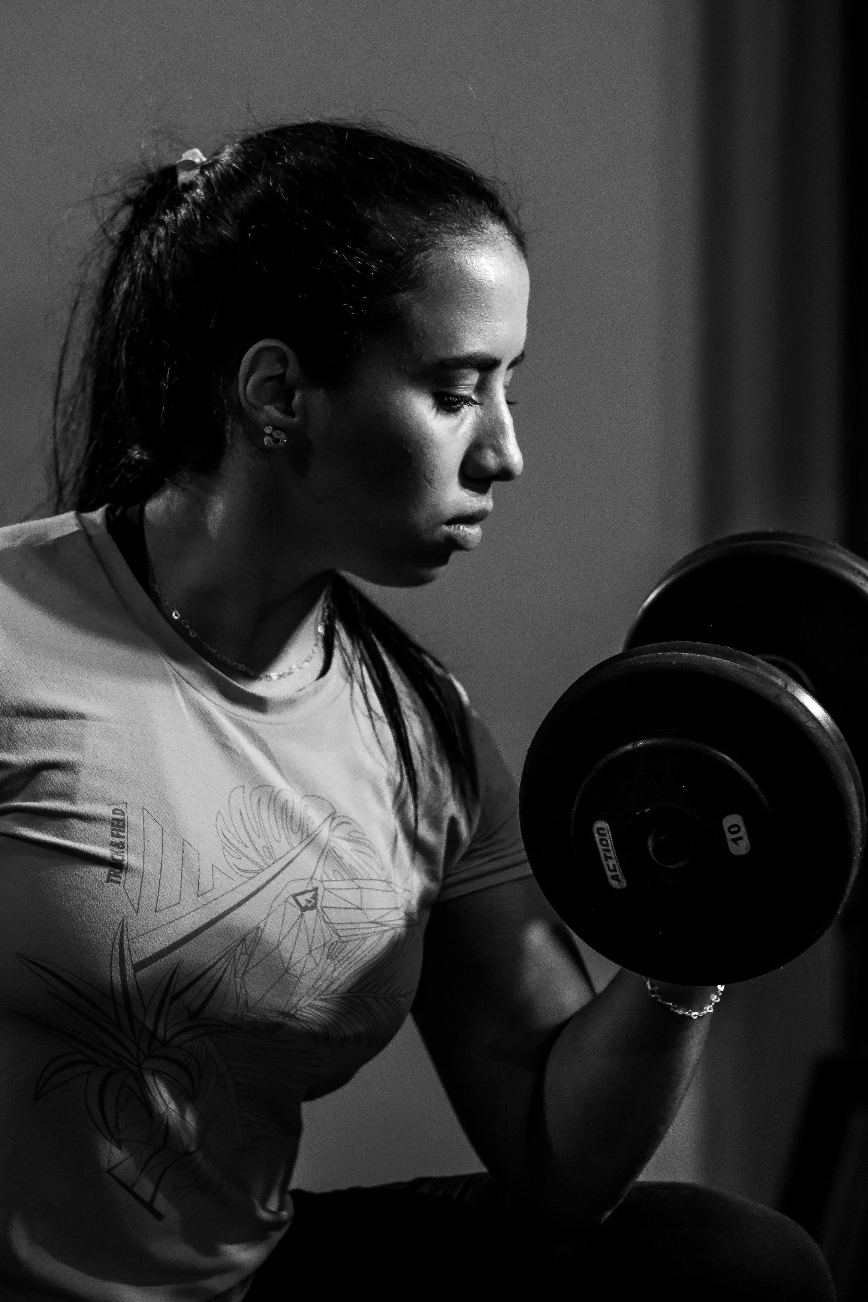 Focused woman building strength with a dumbbell in a gym setting.