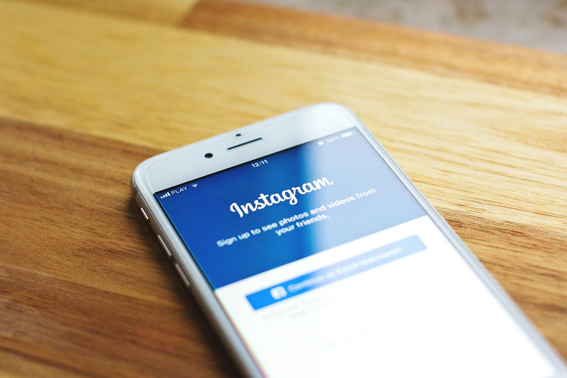 Close-up of a smartphone showing Instagram login on a wooden table.