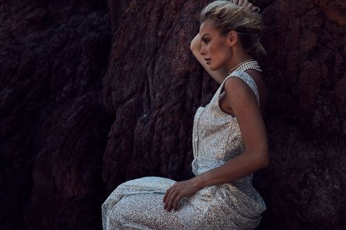Free A stunning woman in a sparkly gown poses dramatically against rugged rocks. Stock Photo