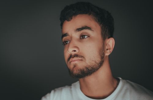 Free Portrait of a young man with a beard looking thoughtful in a studio setting. Stock Photo
