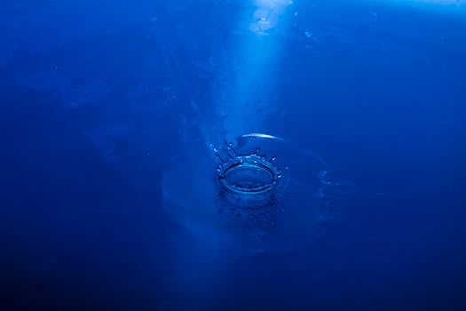 特写镜头捕捉了水花、蓝色背景上的涟漪与水滴，既展现了动态之美，又传递出宁静之感