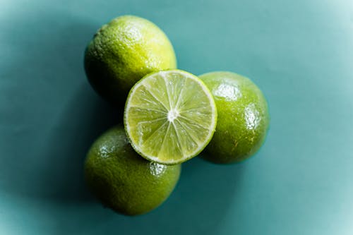 Free Top view of fresh ripe halved and whole limes stacked on green background Stock Photo