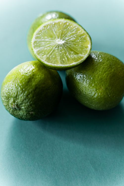 Free From above of halved juicy lime placed on whole unpeeled fruits on green surface Stock Photo