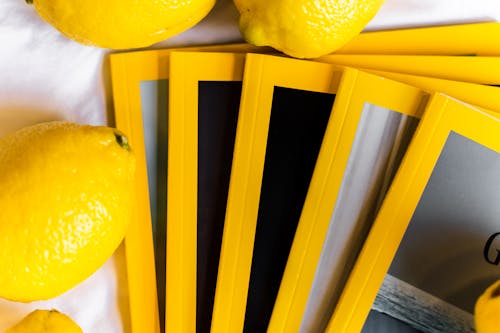 Free Top view of stack of similar books with yellow edges placed on white table near fresh whole lemons in daylight Stock Photo
