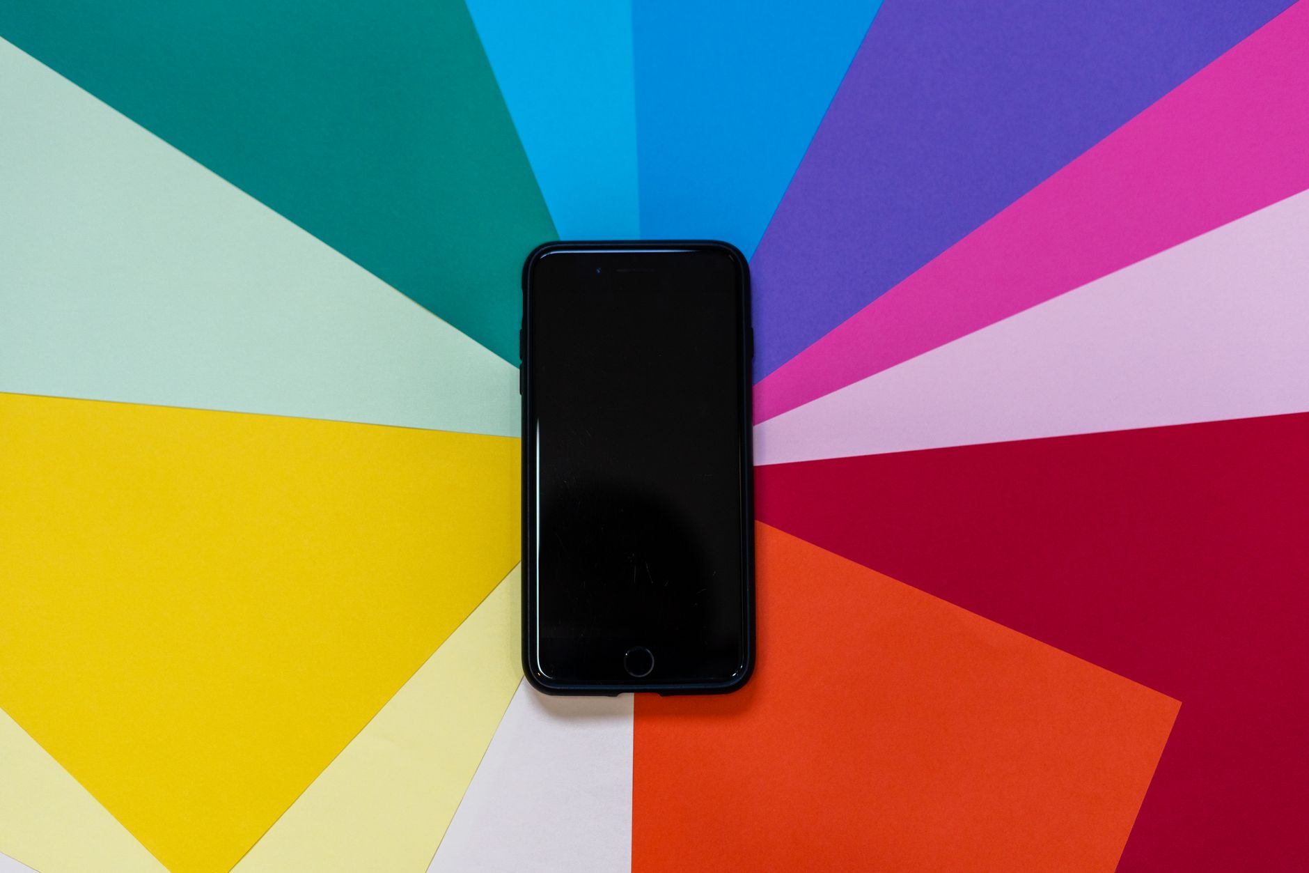 A smartphone placed on a colorful paper background, showcasing vibrant hues in a flatlay style.