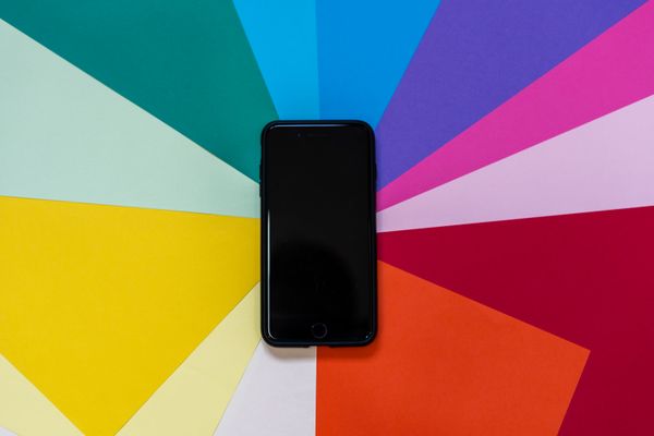 Phone resting on a fan of coloured paper — photo by Enric Cruz López on Pexels