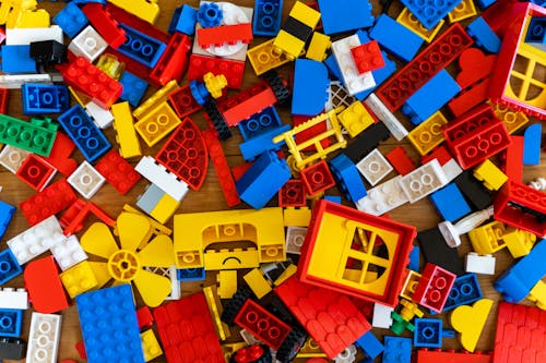 Top view of various pieces of colorful plastic construction toys scattered on wooden floor as abstract background