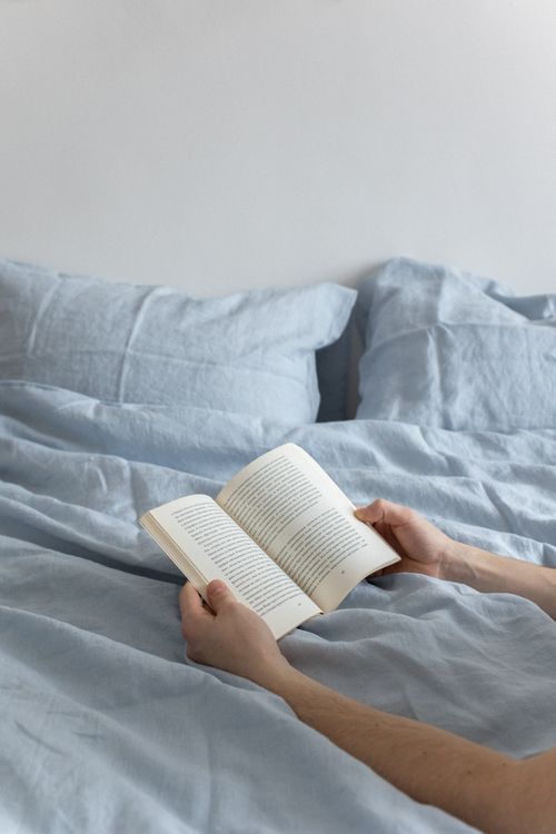 Free A person reading a book in bed, offering a peaceful, indoor atmosphere. Stock Photo