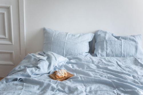 Free A tranquil bedroom scene featuring a croissant on a light blue bed, creating a cozy and inviting ambiance. Stock Photo