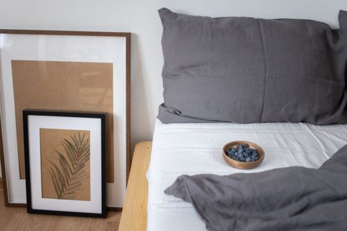 Free A cozy bedroom scene featuring minimalist art and a wooden bowl of blueberries on the bed. Stock Photo