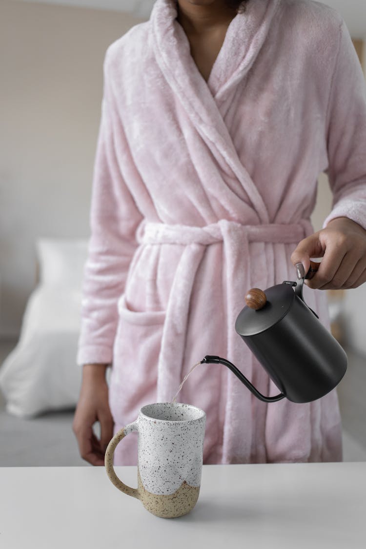 A Person Pouring Water In The Cup