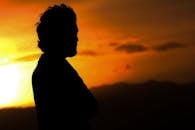 在阿富汗喀布尔，一个男人站在充满活力的日落剪影中，天空温暖，太阳发光