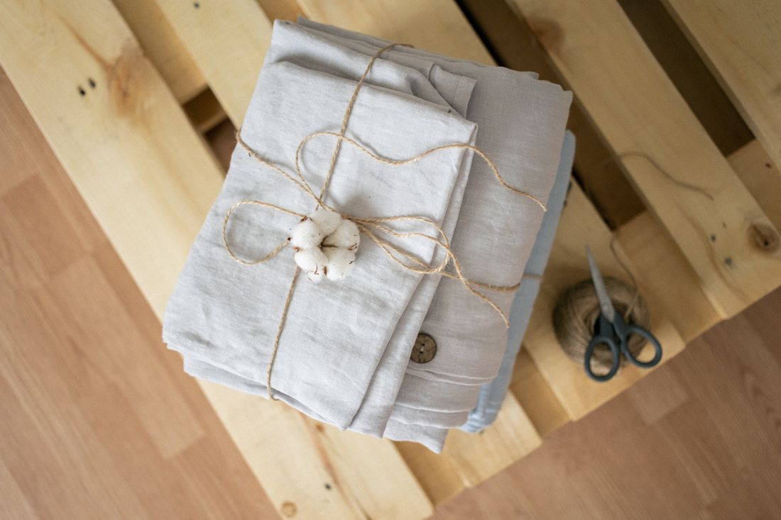 Folded natural linen tied with twine and a cotton boll — photo by KATRIN BOLOVTSOVA on Pexels