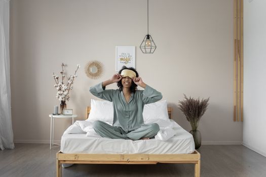A woman enjoys a peaceful morning in pajamas, sitting comfortably in a cozy bedroom.
