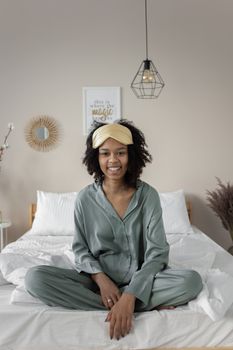 A happy woman in pajamas enjoying a peaceful morning in her cozy bedroom.