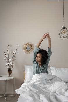 Serene morning scene with woman stretching in a cozy, modern bedroom setting.
