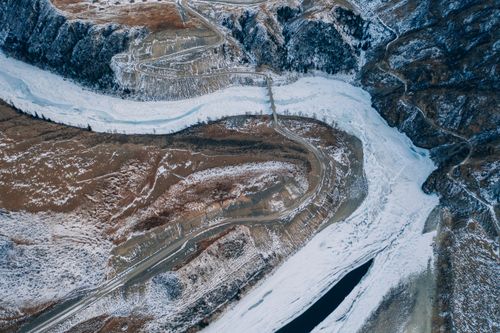Free Stunning aerial view of snow-covered Altai Mountains with winding roads and frozen river. Stock Photo