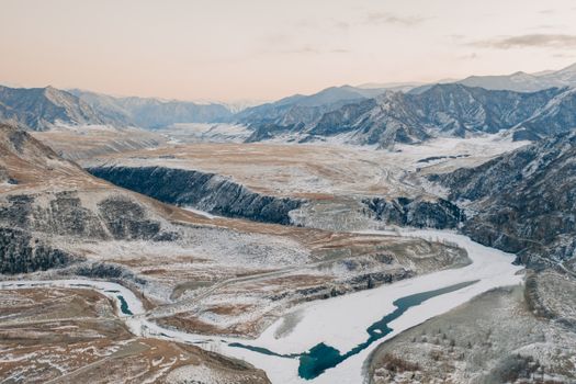 Stunning winter aerial view of snow-covered Altay Mountains and frozen river in Russia.