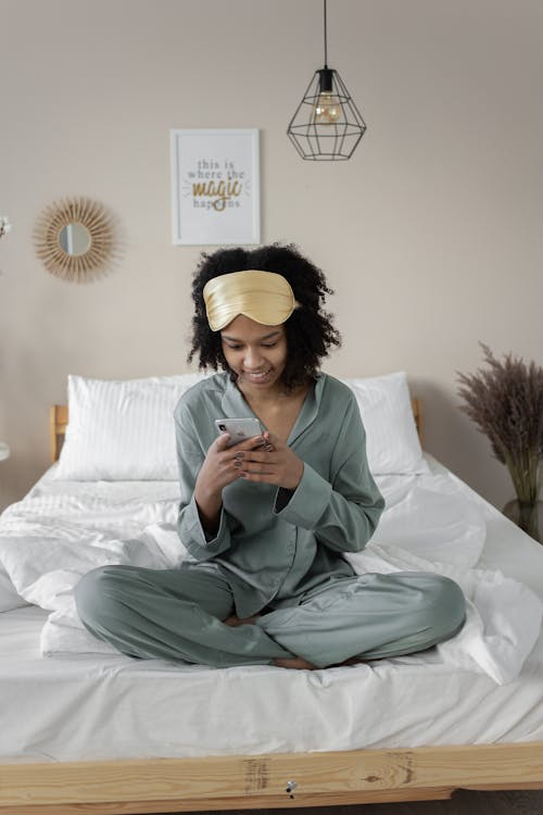 Free Woman Wearing Pajama and Sleeping Mask Using Phone in Bed  Stock Photo