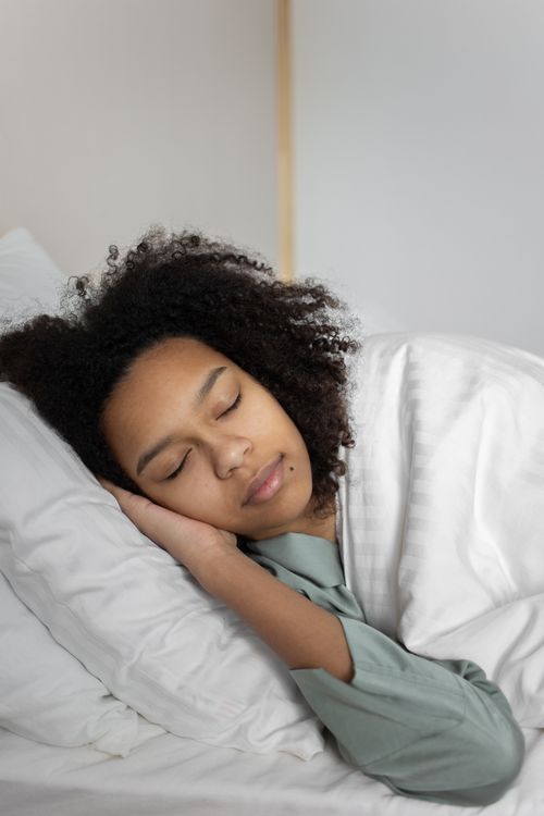 Woman lying on bed covered with a blanket