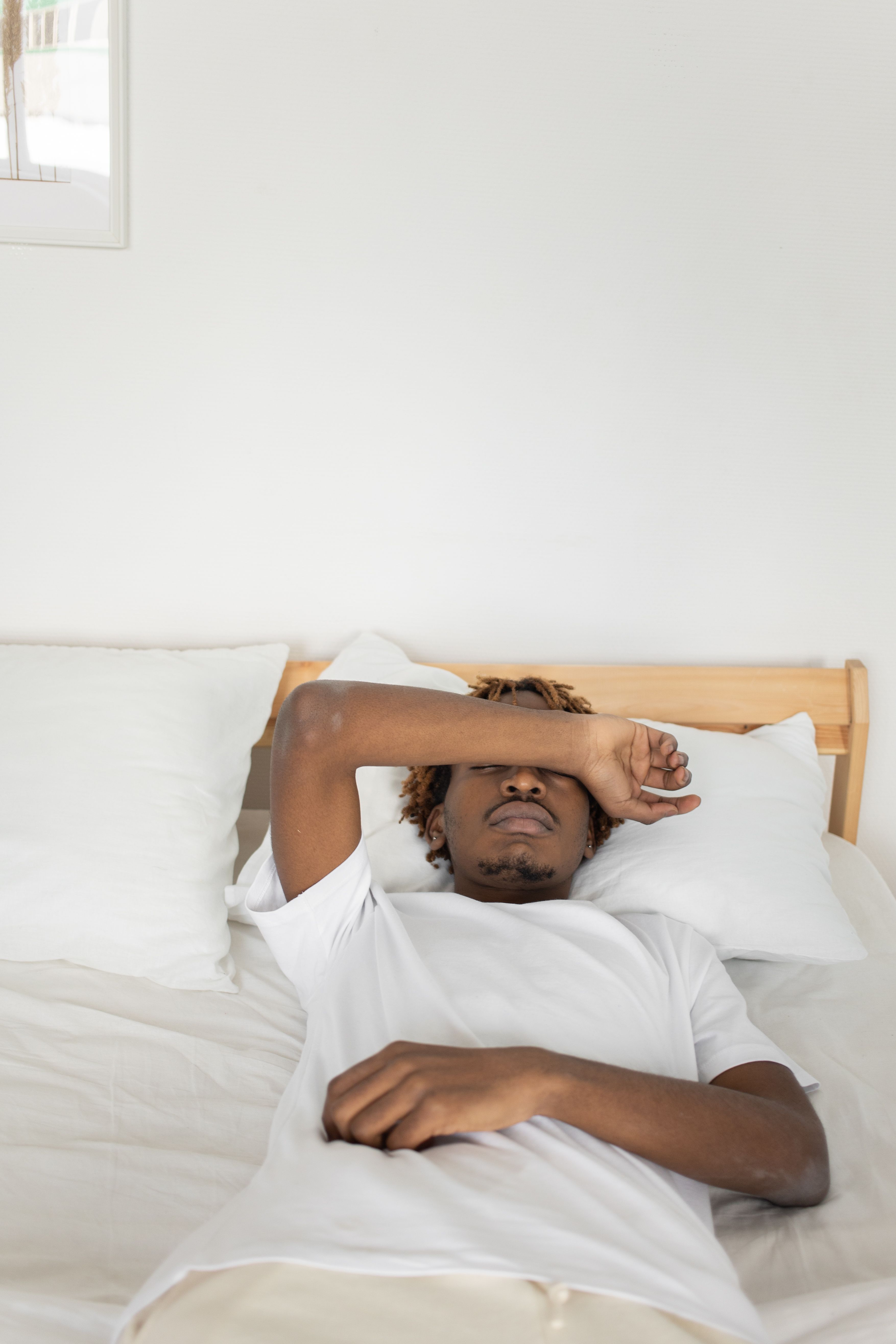 Man resting comfortably on a bed in a minimalist setting, showcasing relaxation and ease.
