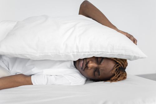 Free A man enjoying a peaceful nap indoors under a white pillow, conveying relaxation. Stock Photo