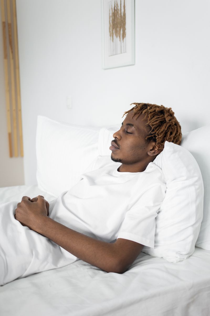 A Black man sleeps in bed. Loud snoring and waking unrested can be signs of sleep apnea, a condition that often goes undiagnosed in Black adults.