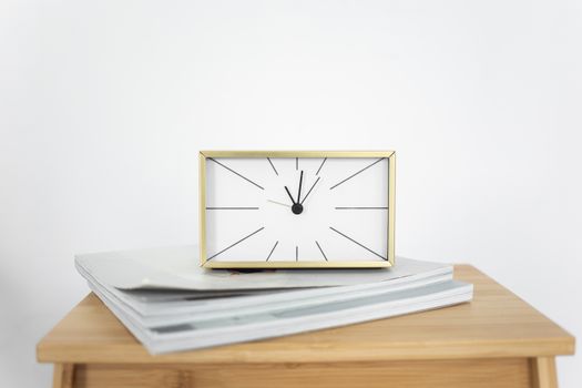 Stylish minimalist clock with gold frame on wooden table, ideal for modern interiors.