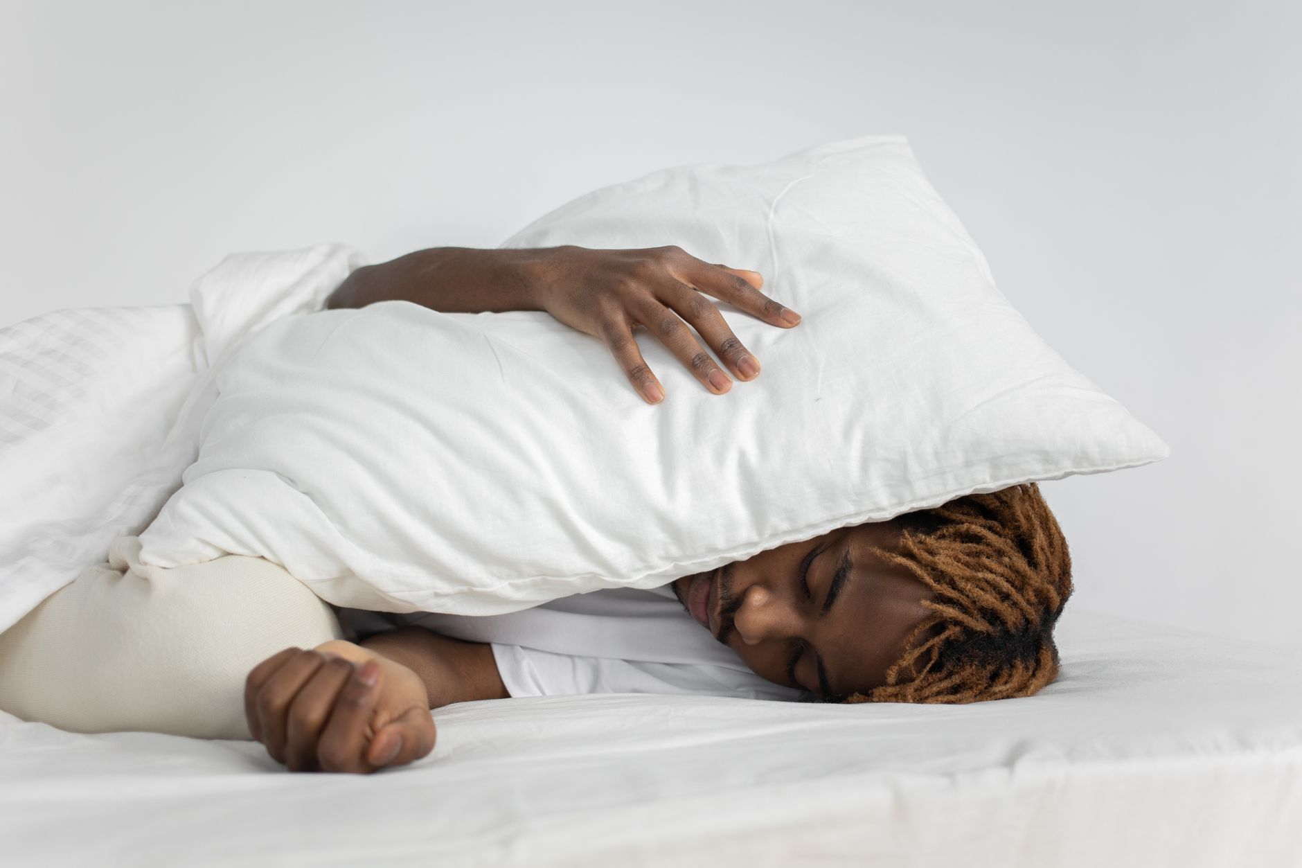 A person sleeping peacefully with a pillow covering their face, showcasing relaxation and rest.