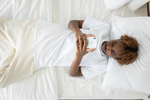 Free High-Angle Shot of a Man Lying Down on Bed while Using His Cellphone Stock Photo
