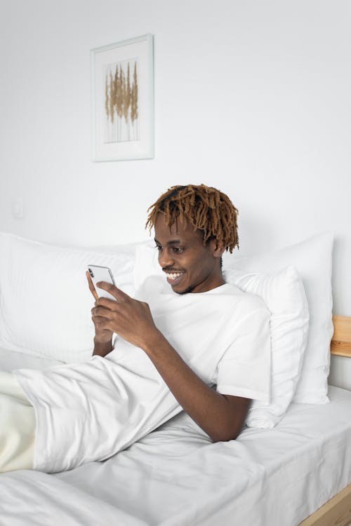 Man Lying on Bed While Using Cellphone