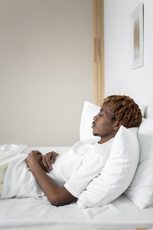 Free Man in White Shirt Lying on Bed Stock Photo