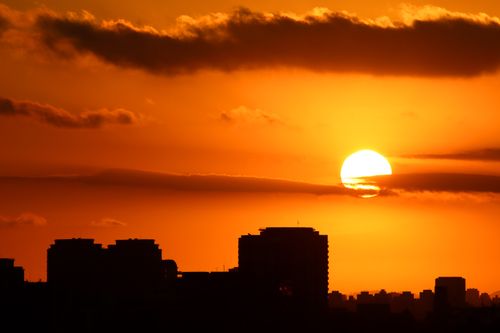 Free Dramatic city skyline silhouette against a vibrant sunset sky. Stock Photo