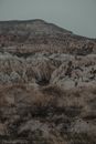 Rocky formations located on grassy terrain with shrubs located in famous national park of Cappadocia in Turkey against cloudless sky
