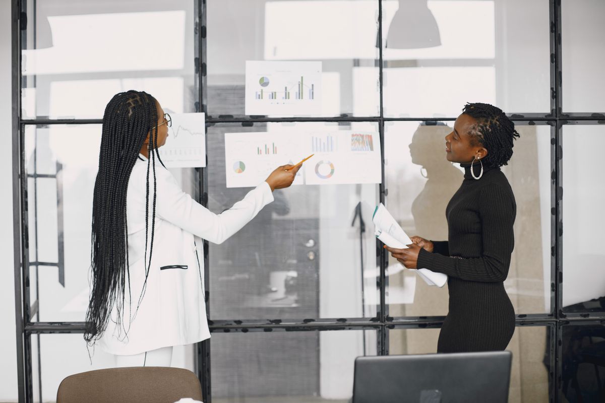 Black businesswomen reviewing charts in a technology-focused office
