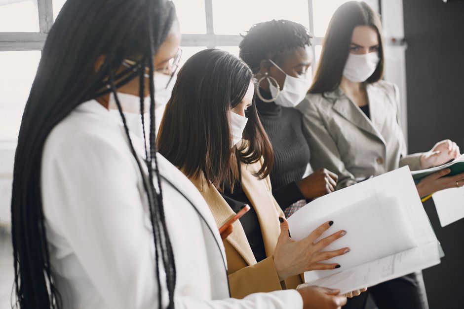 Un grupo diverso de mujeres trabaja juntas en un entorno de oficina, mostrando trabajo en equipo y colaboración.