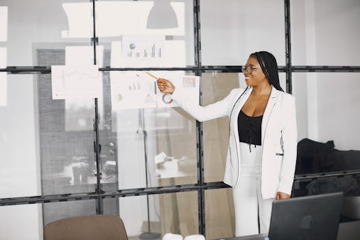 African American woman presenting charts in a modern office setting.