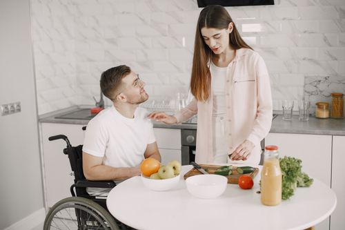 Free A man in a wheelchair and a woman preparing food together in a modern kitchen. Stock Photo