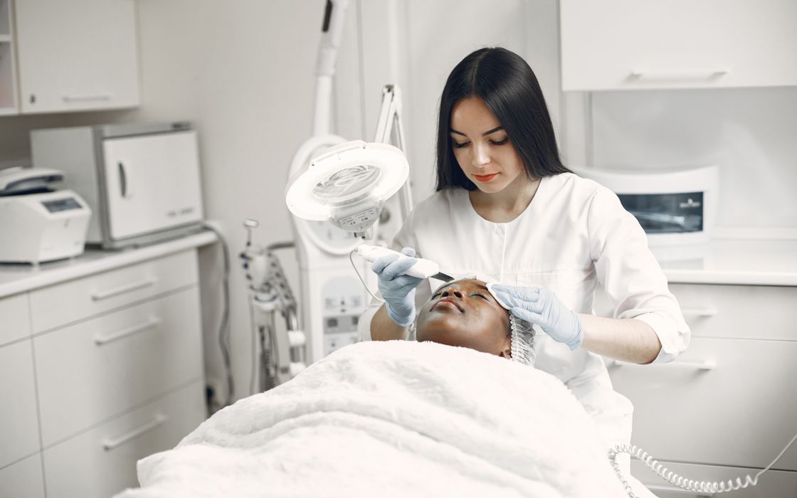 Aesthetician providing a rejuvenating facial treatment to a client in a modern spa clinic setup.