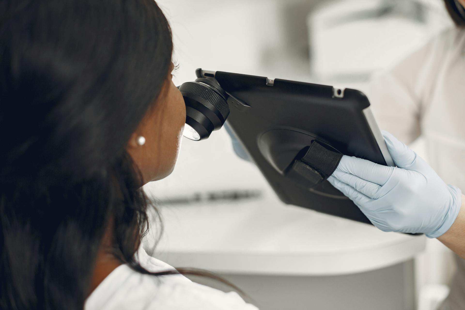 Dermatologist examining a patient's skin using a digital dermatoscope and tablet for precision observation.