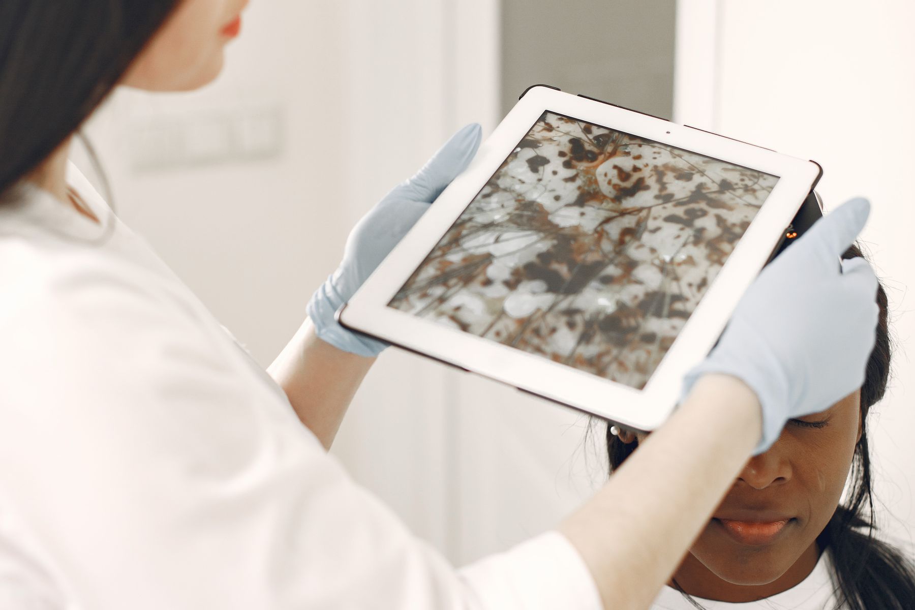 Dermatology clinician reviewing a patient skin assessment on a tablet during a consultation