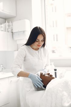 Beautician performing facial treatment on a relaxed woman in a modern spa.