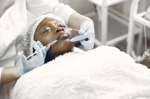 Free A woman receiving a cosmetic injection with syringe in a medical setting. Stock Photo