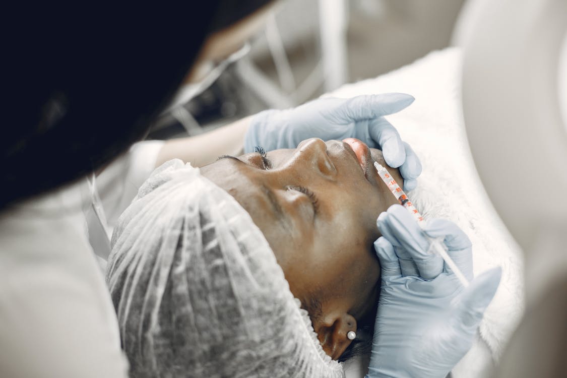 Free Close-up of a woman receiving a cosmetic lip injection in a clinic setting. Stock Photo
