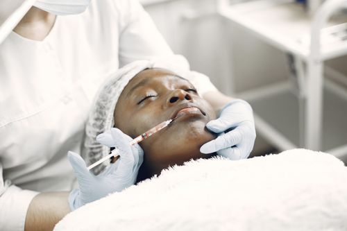Free A beautician performs a delicate lip injection on a woman lying with eyes closed. Stock Photo