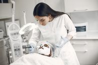 A beautician applies a face mask to a client in a beauty clinic, focusing on skincare and relaxation.