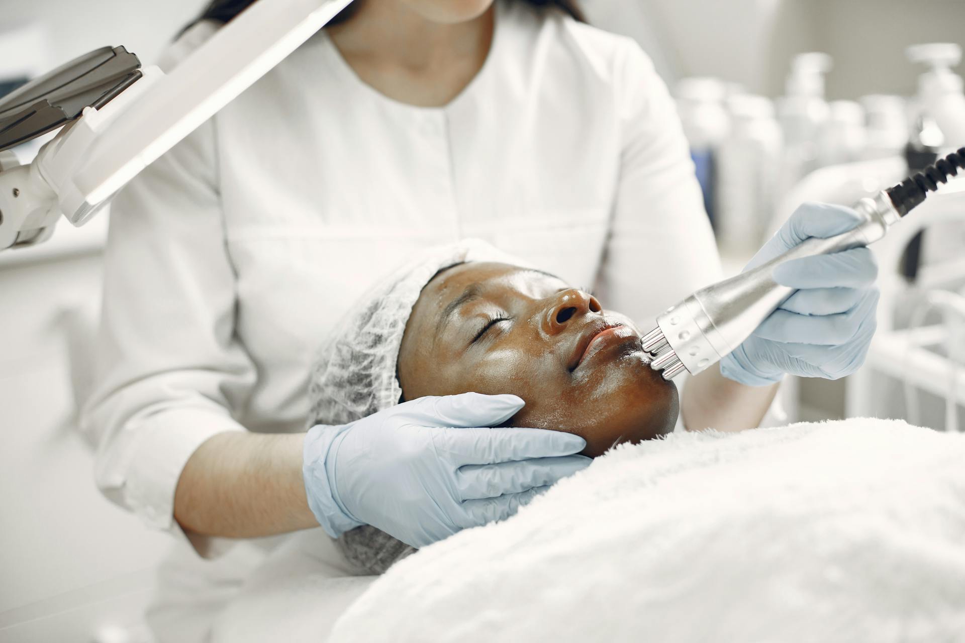 A dermatologist performing a laser treatment on a relaxed client in a clinic.