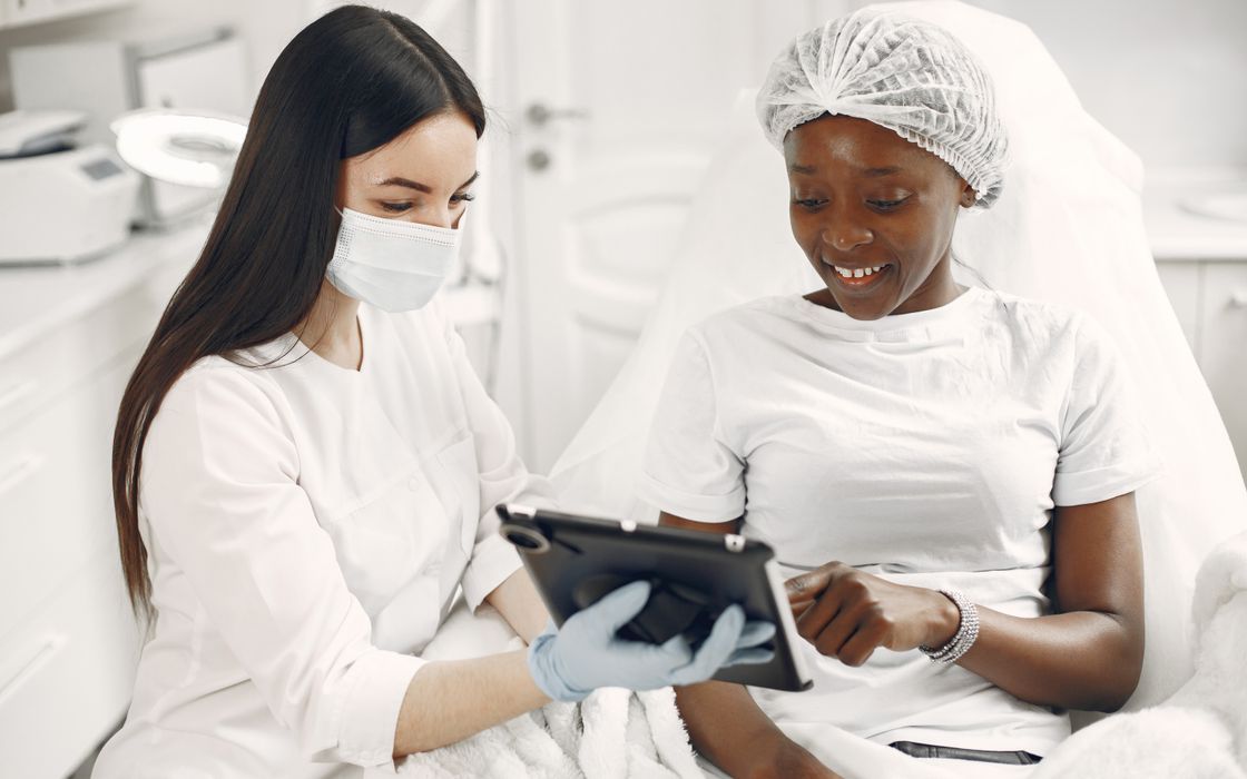 Patient and clinician reviewing information on a tablet together in a clinic treatment room