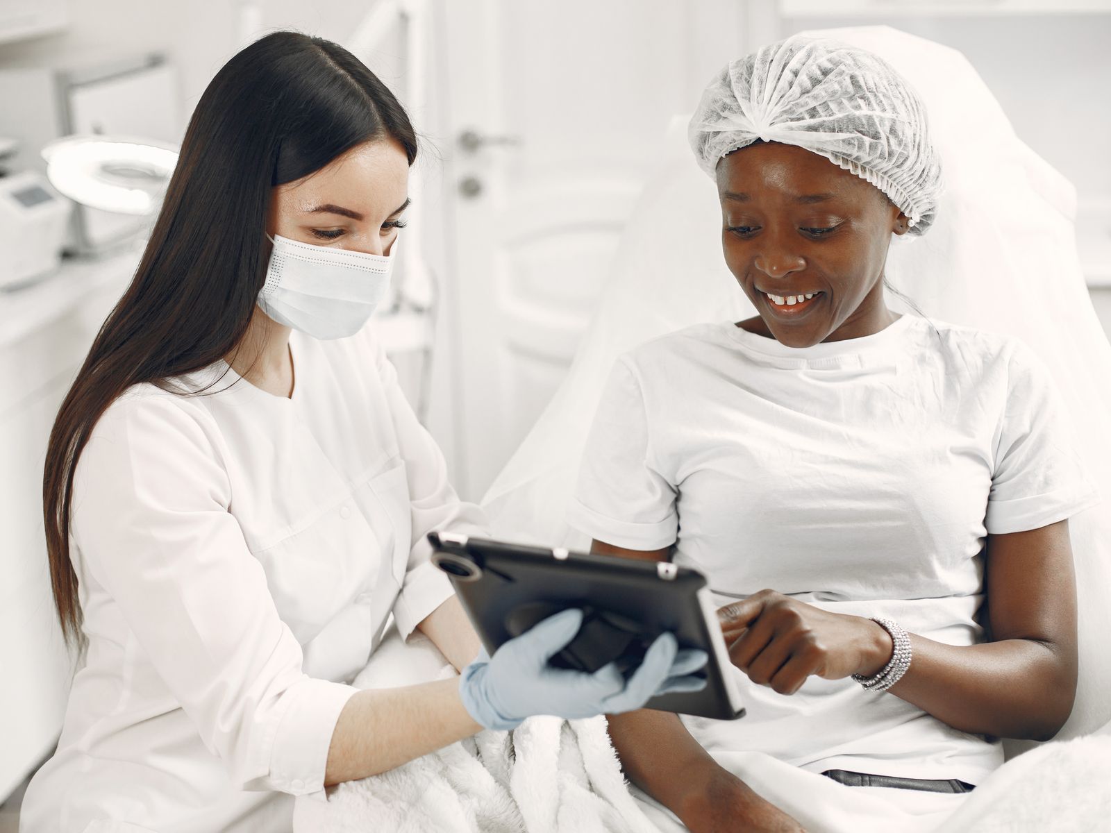 Smiling patient and skin specialist reviewing information on a tablet