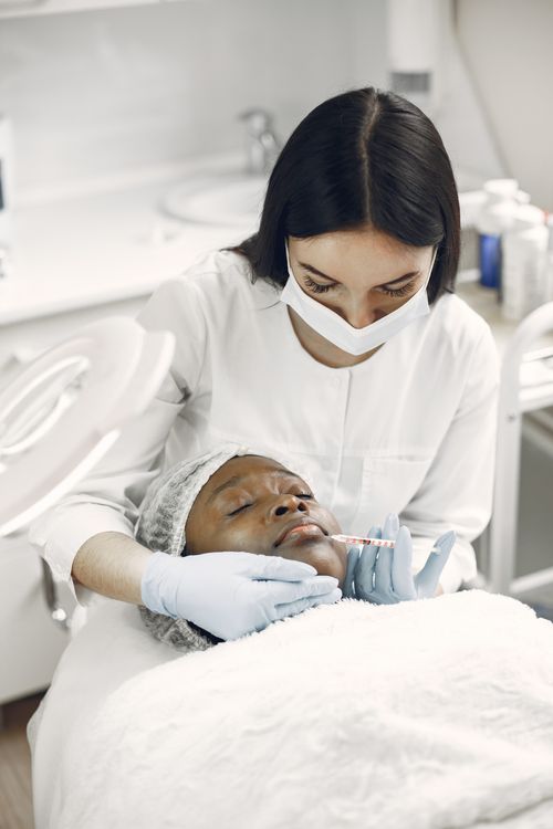 Free Beautician applying facial treatment to woman in spa clinic, promoting skincare and self-care. Stock Photo